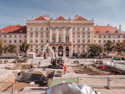 Eine Baustelle mit Arbeitern und einem Bagger am MQ-Hauptplatz