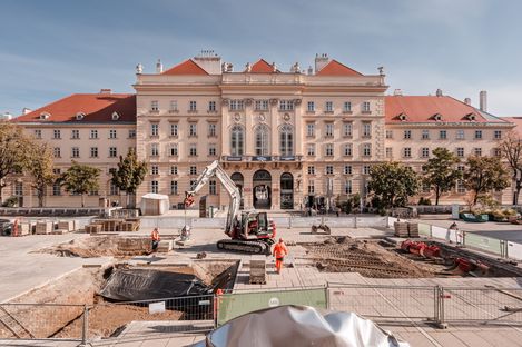 Eine Baustelle mit Arbeitern und einem Bagger am MQ-Hauptplatz