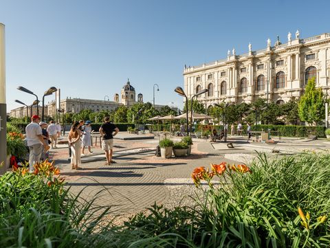 Visitors spend time in the landscaped outdoor area of MuseumsQuartier Vienna, with views of the Kunsthistorisches Museum and other historic buildings.