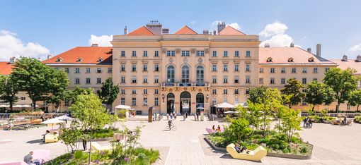 Blick über den begrünten MQ Haupthof auf den historischen Fischer-von-Erlach-Trakt des MuseumsQuartier Wien.