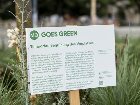 MQ goes green Beschilderung in einem Blumenbeet.