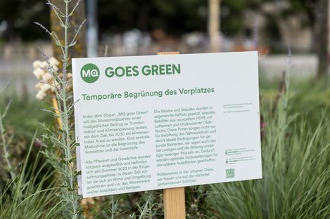 MQ goes green Signage in a flower bed.