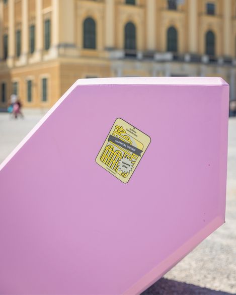 Detailaufnahme eines rosa Enzi-Sitzmöbels mit „Imperial Living Vienna 2026“-Sticker vor Schloss Schönbrunn.