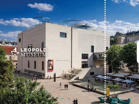 Frontalaufnahme des Leopold Museum am MQ Haupthof. Menschen spazieren über den Platz. Die Sonne scheint.