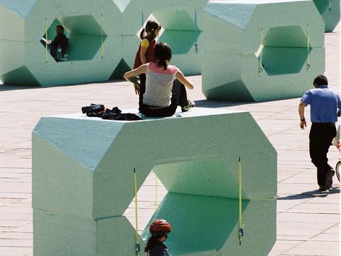 Kind fährt mit dem Fahrrad durch das MuseumsQuartier Wien, im Hintergrund hellgrüne MQ Sitzmöbel und spielende Menschen