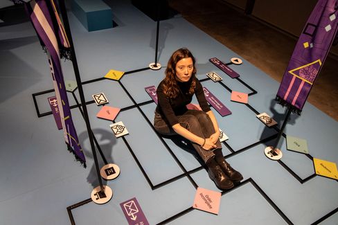 Person sitting on the floor within a game board marked by colored cards and lines.