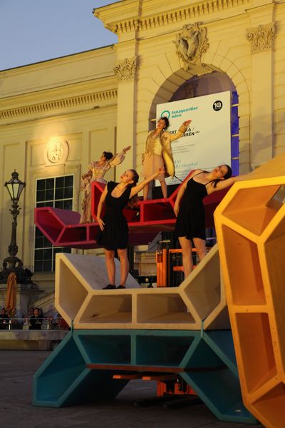 Contemporary dancers on elevated Enzis in front of historic architecture at MuseumsQuartier