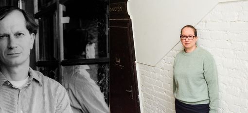 Two people, one in black-and-white facing forward and the other in color standing sideways against a white brick wall