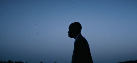 Silhouette eines Mannes im Profil vor einem dunklen Himmel und Gewässer im Hintergrund