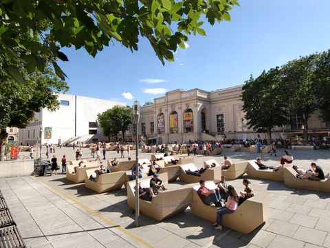 Blick über den MQ Haupthof mit zahlreichen beigen Enzi-Sitzmöbeln und Menschen, die entspannen und zusammensitzen