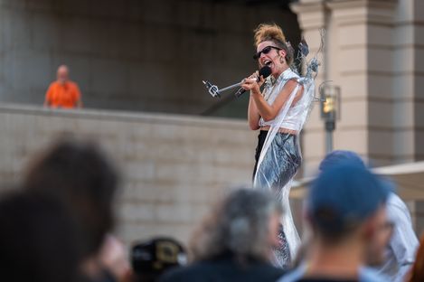 Woman with updo hairstyle and sunglasses sings in front of a crowd