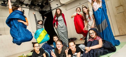 Children are on stage at DSCHUNGEL WIEN with their sleeping bags.