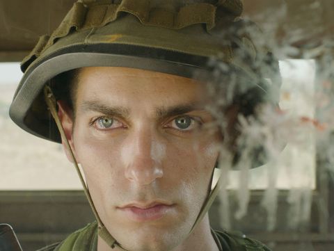 A film still with a close-up of a face wearing a military helmet in a lookout post.