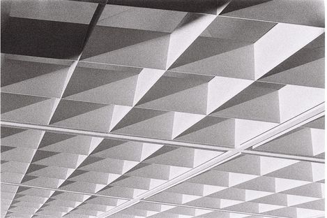 Schwarz-weiße Aufnahme einer Decke mit einem Muster aus dreidimensionalen, pyramidenförmigen Elementen in Reihen.