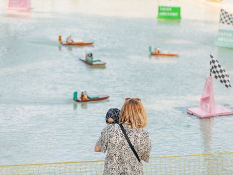 Aquadrome, MuseumsQuartier Wien. Eine Frau und ein Kind beobachten kleine Schiffe in einem Wasserbecken.