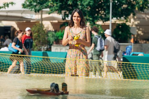 Visitor controlling a model boat at the Aquadrome in MuseumsQuartier Vienna, an interactive outdoor summer activity.