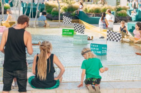 Families and children watching model boat races at the Aquadrome in MuseumsQuartier Vienna.