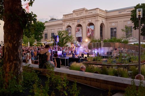Crowd at an outdoor event in front of a historic building with columns and large banners