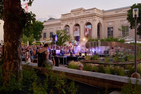 Crowd at an outdoor event in front of a historic building with columns and large banners