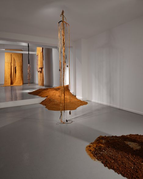 Fabric panels and mounds of earth in a minimalist exhibition setting.