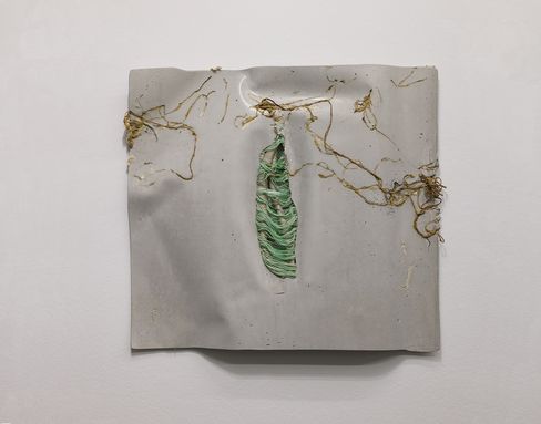 Wall piece made of light material with embedded roots and a green fiber structure.
