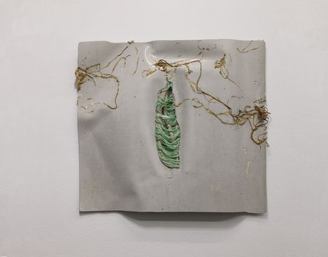Wall piece made of light material with embedded roots and a green fiber structure.