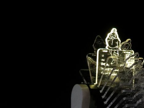 Leuchtende, transparente Acrylfiguren mit Comiczeichnungen auf schwarzem Hintergrund