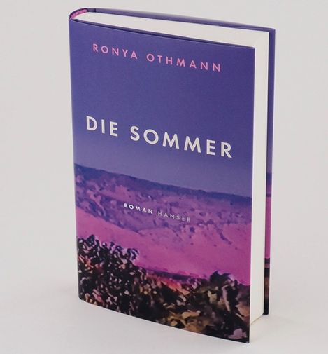 Book titled "Die Sommer" by Ronya Othmann with a cover showing a landscape of mountains and trees in purple and pink tones.