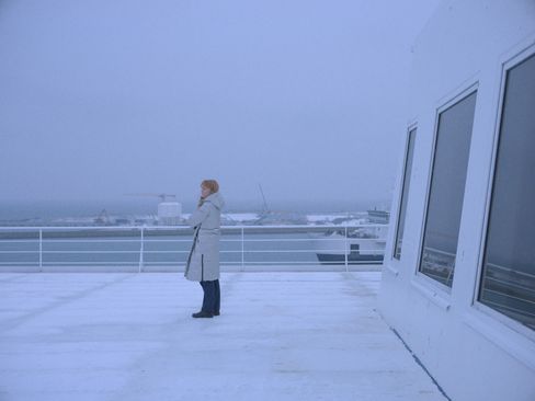 Eine Person steht steht auf einen Schiffsdeck und blickt in die Ferne. Es ist stürmisch und wirkt sehr kalt.