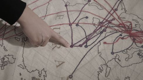 Hand pointing to a spot on a map with multiple lines connecting various locations.