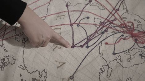Hand pointing to a spot on a map with multiple lines connecting various locations.