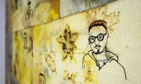 Wall with multiple square yellowish tiles featuring schematic portraits and floral patterns.