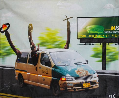 Old yellow-green minibus with damaged front and two large sculptural tree-like objects protruding from it on a road with blurred background and a billboard.