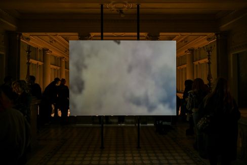 Large-scale projection of a cloud-like abstract scene inside a historic interior with visitors.