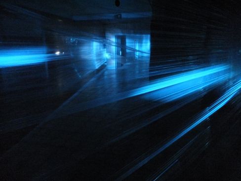 Dunkler Raum mit mehreren horizontal verlaufenden, leuchtend blauen Lichtstreifen.
