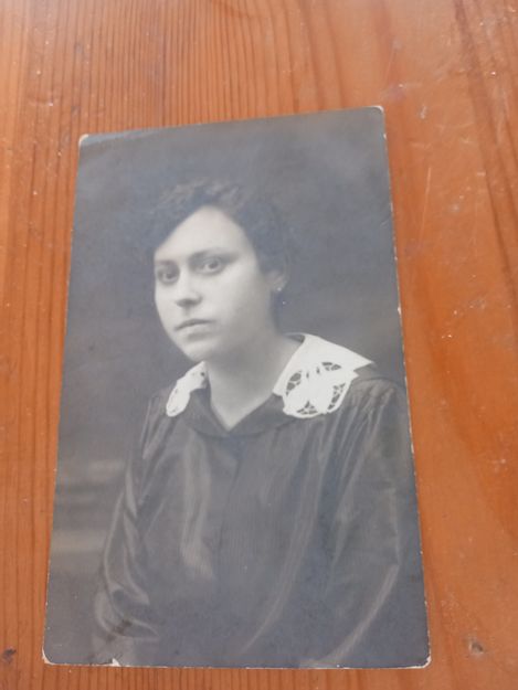 Portrait of a person wearing dark clothing with a white lace collar against a blurred background.