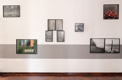 Wall with multiple framed photographs and texts of various sizes and arrangements above a gray stripe.