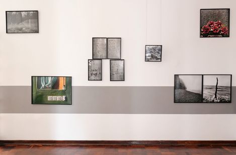 Wall with multiple framed photographs and texts of various sizes and arrangements above a gray stripe.