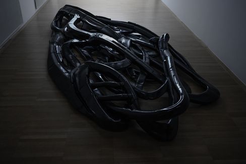 Large tangled black plastic object on a light floor indoors.