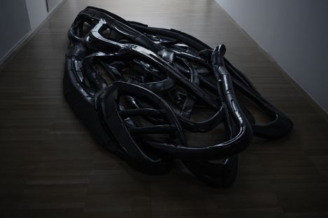 Large tangled black plastic object on a light floor indoors.