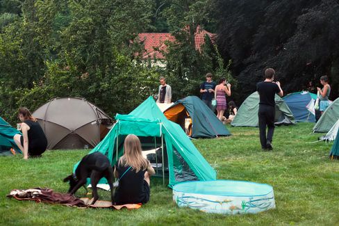 People with tents on a grassy field during an outdoor event in a park-like setting.