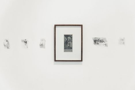 Fünf schwarz-weiße Drucke an einer weißen Wand, mittig ein gerahmter Druck, die anderen vier ungerahmt und kleiner.
