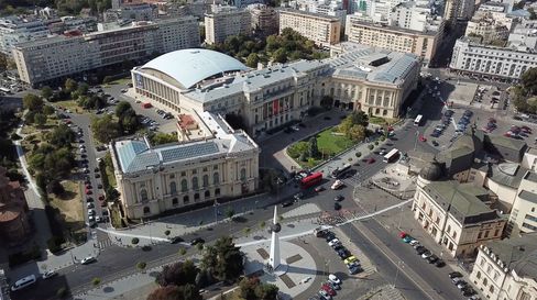 Luftaufnahme eines großen Museumsensembles mit Kuppelbau, umgeben von Straßen, Autos und städtischer Bebauung.