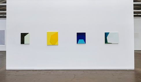 Four abstract paintings with geometric shapes in different colors on a white wall in an exhibition space