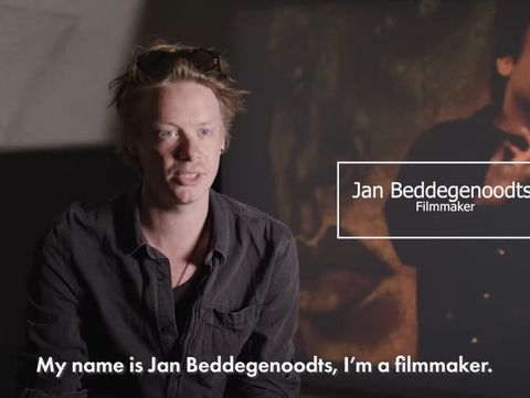 A person sits in a dimly lit room, wearing a dark shirt and sunglasses on their head. Text reads, "My name is Jan Beddegenoodts, I'm a filmmaker."