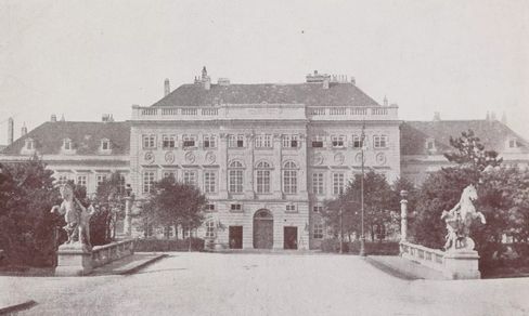 Schwarz-weiße Aufnahme eines großen historischen Gebäudes mit zwei Reiterstatuen auf Brückengeländern im Vordergrund