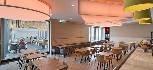 Bar area at Café Leopold with long wooden counter, bar stools and modern ceiling lights