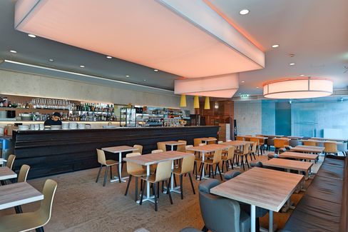 Interior view of Café Leopold at MuseumsQuartier Vienna with bar counter, wooden tables, and modern ceiling lighting.