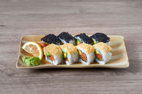 Sushi rolls with salmon and avocado, topped with black and white sesame seeds, served on a rectangular plate