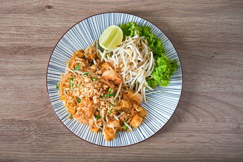 Pad Thai noodles with shrimp, peanuts, bean sprouts and lime on a round plate